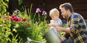 A man and a small child are looking at the flowers in a garden
