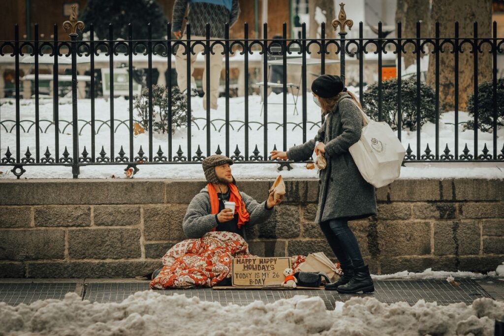 a woman talks to a person sleeping rough on the streets