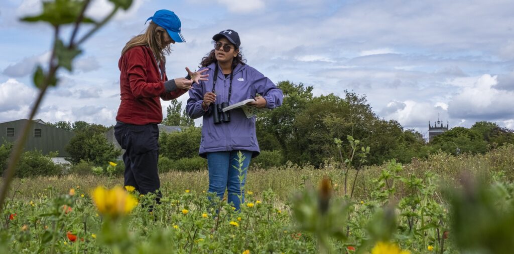 Sam Turley stands in a field with a farmer