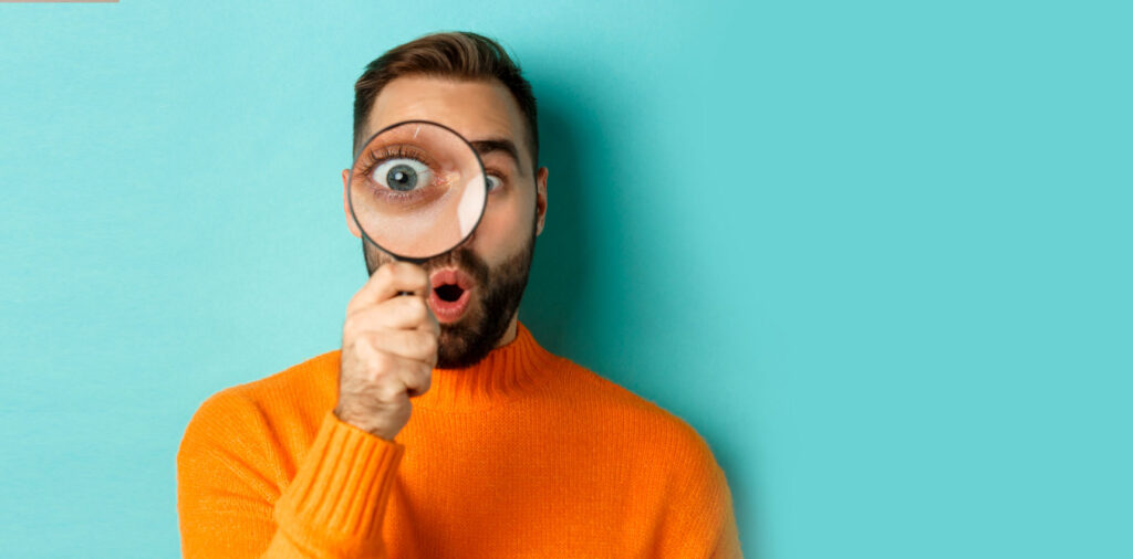 Man looking through a large magnifying glass